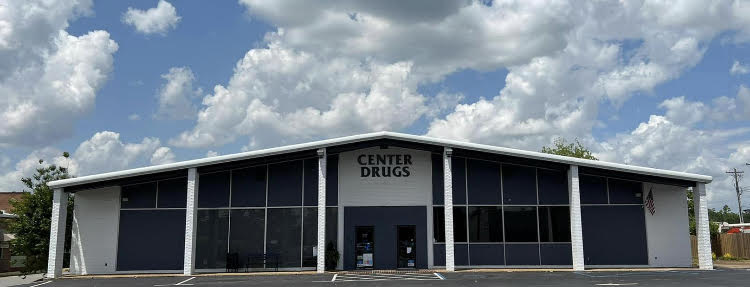 Center Drugs storefront with white-painted brick beneath a partly cloudy sky