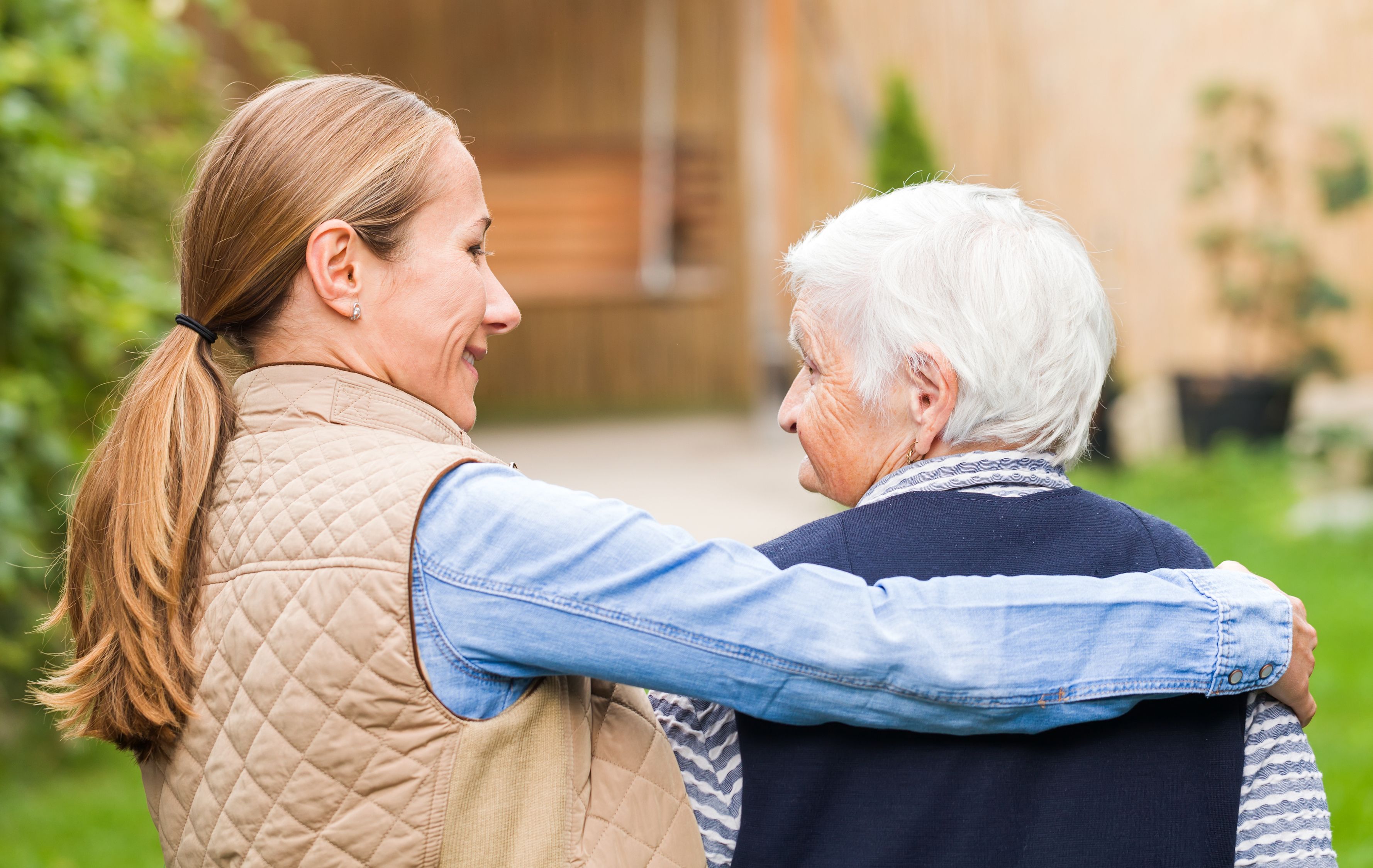 Woman with her arm around an older woman outdoors